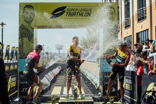 Richard Murray and Jonathan Brownlee shower Kristian Blummenfelt with champagne atop the podium